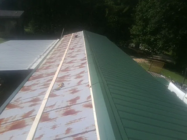 Old rusted panels beside newly installed green metal roofing — Wind Damage Roof Repair by Roofing Brothers in Monterey Park