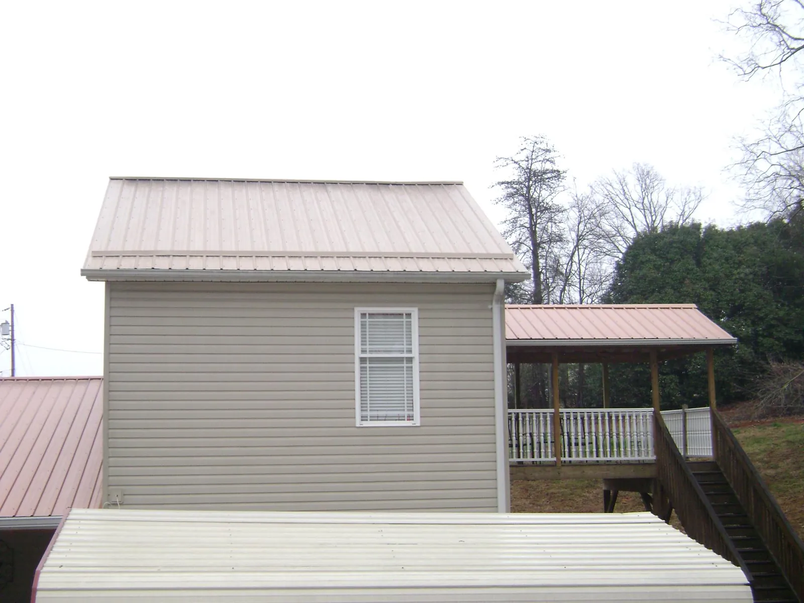 Tan metal roofs on a two story addition and attached porch, from a Roof Replacement job in Monterey Park