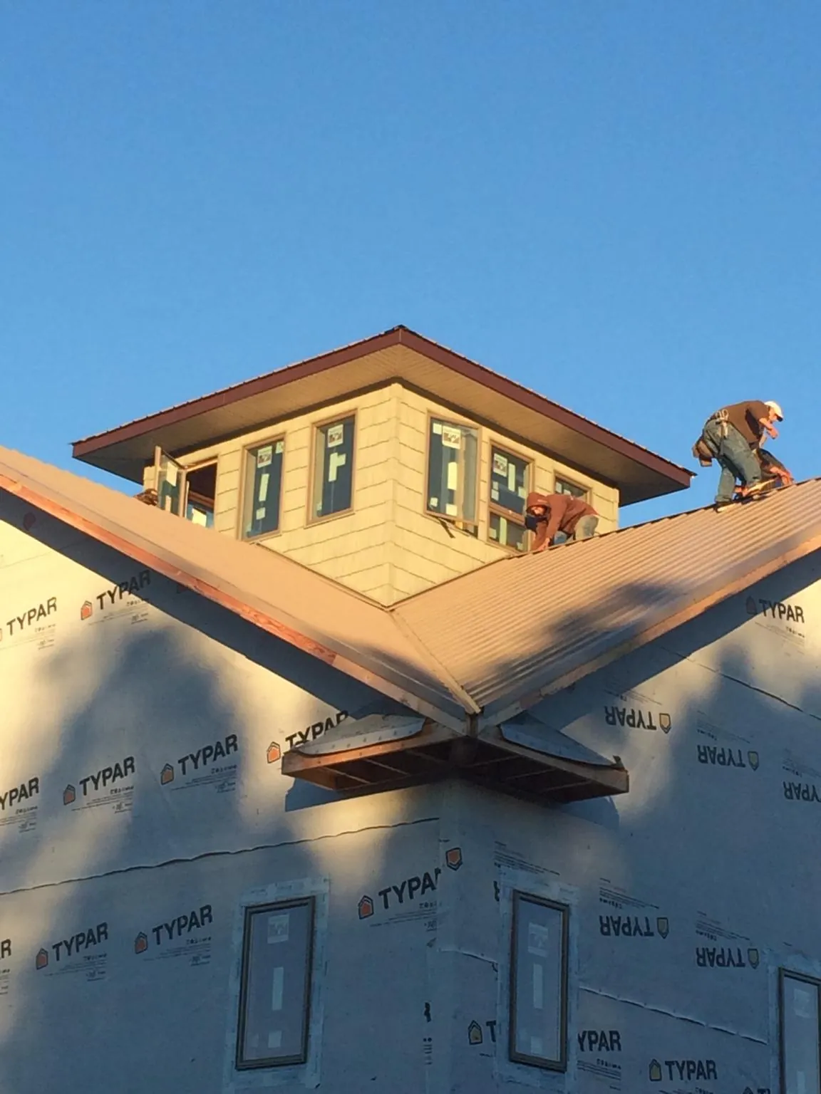 Roofers working around a rooftop cupola on a new metal roof at sunset — Roof Waterproofing in Monterey Park by Roofing Brothers